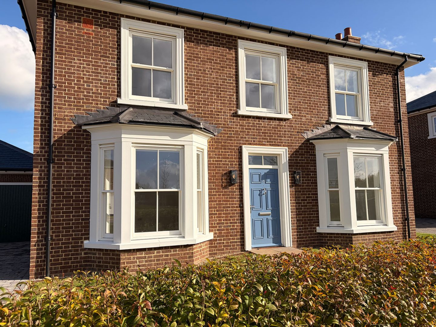 White sliding sash bay windows on a red brick house