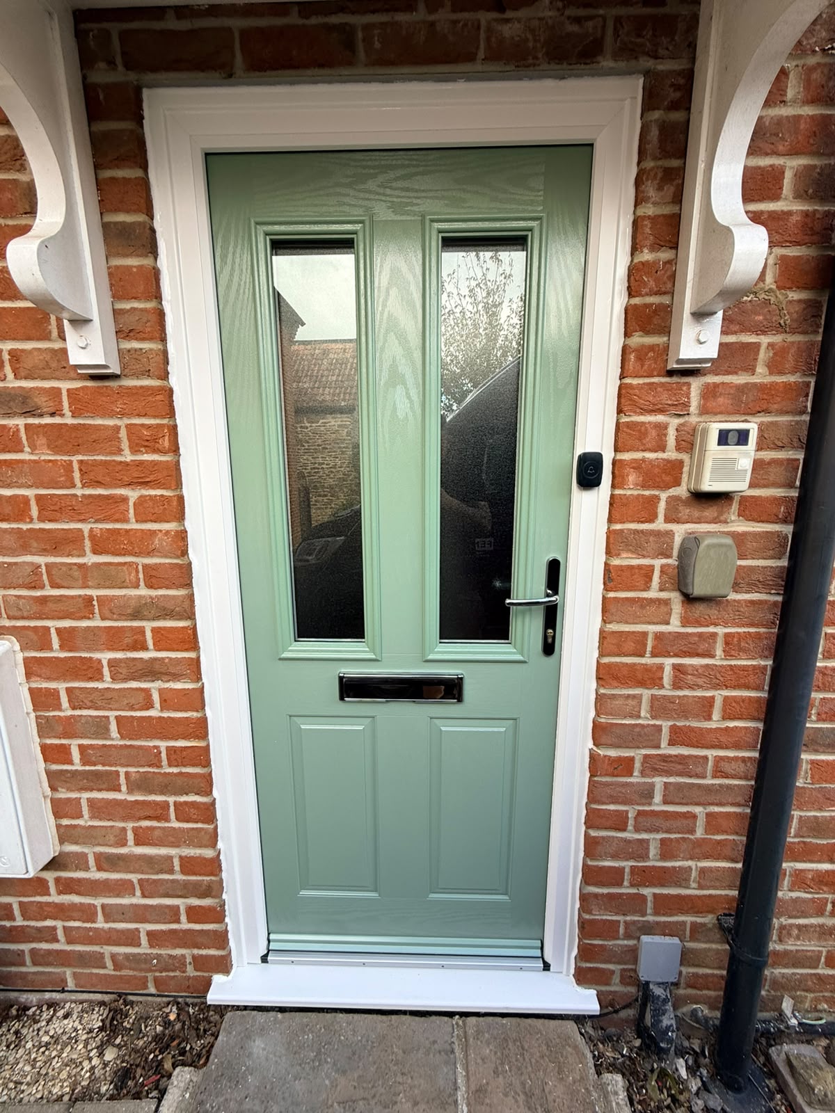 Chartwell Green composite front door with two glazed panels fitted on a red brick house in Henstridge, Somerset